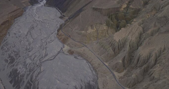 Mustang Nepal, static aerial shot over a wide braided river network running alongside dry, rugged mountain canyon walls.