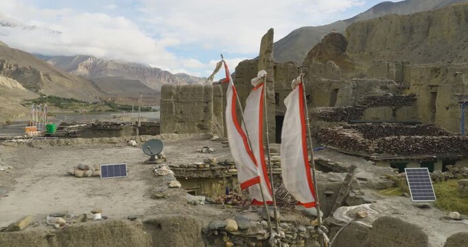 Mustang Nepal, lateral gliding shot of historic mud brick houses and traditional stone architecture in a remote village, distant hills, and river valley , and surrounded by sandy peaks