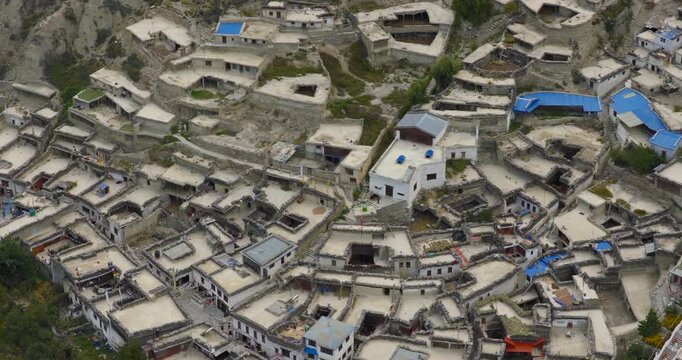 Marpha Mustang Nepal, top down lateral aerial tracking shot gliding across the flat stone roofs and unique architectural landscape of the historic mountain village.