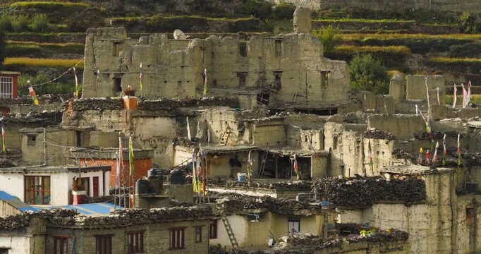 Kagbeni Mustang Nepal, aerial pull-out shot revealing traditional stone architecture and a mix of inhabited and abandoned mud brick houses, nestled between hills and agricultural lands