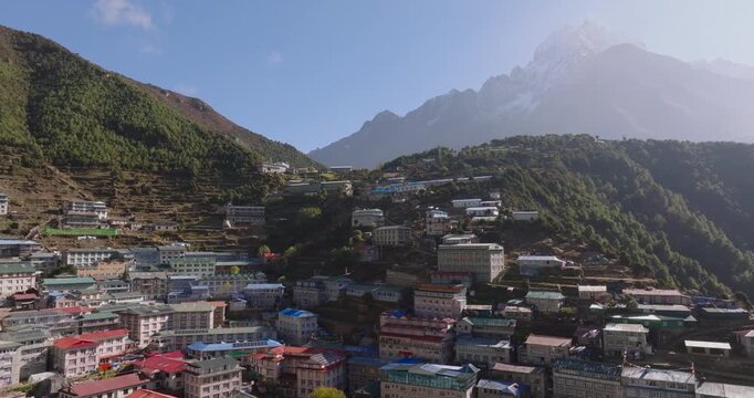 Namche Bazaar, Everest, Nepal. An aerial orbiting shot of the colorful lodges and buildings of the Sherpa town, with the green hillsides and the grand peak of Kongde Ri framing in the background