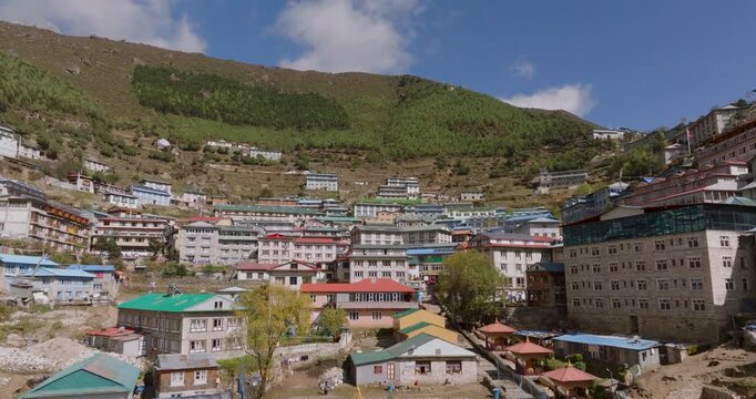 Namche Bazaar, Everest, Nepal, aerial pull-out shot of modern lodges and hotels nestled within the lush green hills on a bright sunny day