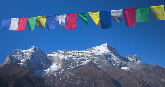 Everest region, Nepal, static shot of the snow capped Kongde Ri mountain range framed below a string of colorful Buddhist prayer flags