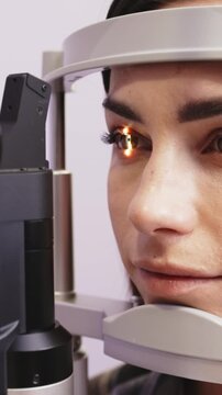 Female patient undergoing diagnostic slit lamp examination with focused light illuminating her eye, showcasing detailed observation in a clinical setting