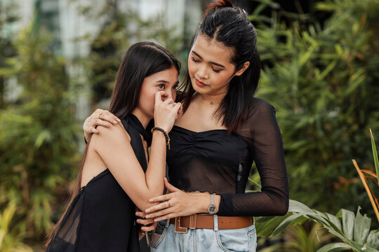 A young Southeast Asian woman becomes emotional while opening up about her personal problems as her close friend offers comfort and support.