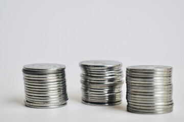Macro detail of three structured columns of silver Malaysian coins on a bright white background, highlighting texture, financial abundance, and compound interest concepts. © Akram