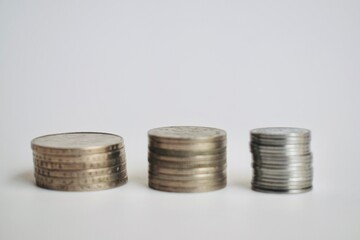 Three neat stacks of Malaysian ringgit coins arranged in a row against a clean white background, representing financial growth, savings, and banking concepts. © Akram