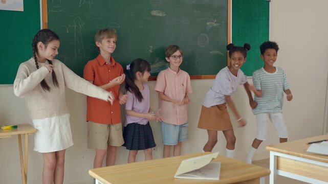 Group of diverse school kids dancing in front of classroom at primary school.
