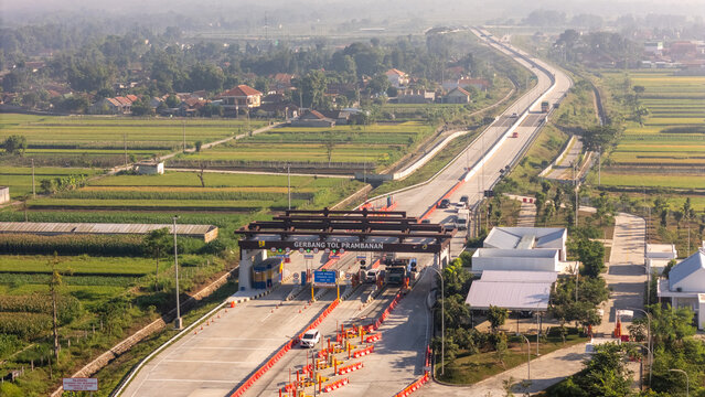 Indonesia - 19 June 2026: Aerial view of the Prambanan Toll Gate surrounded by lush green rice fields and rural landscapes, featuring highway infrastructure under soft morning light.