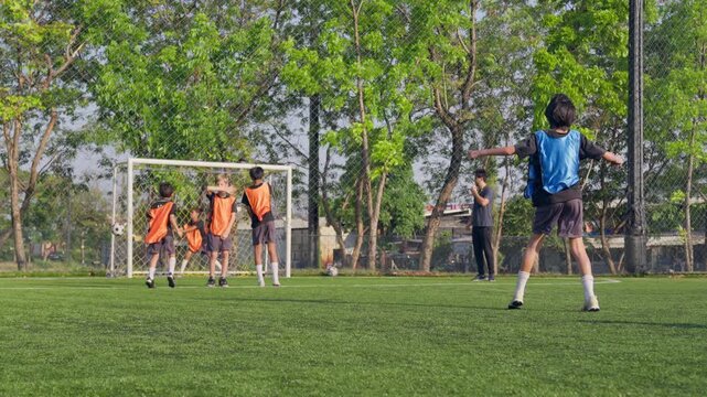 Rear view of young boy playing football on outdoor soccer field. 