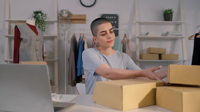 Caucasian woman checking customer orders on laptop in clothing store. 