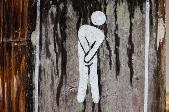 Person symbol restroom urgent need toilet wooden sign outdoor wet humor male icon public facility nature relief emergency funny painted distressed rustic background simple graphic stick figure