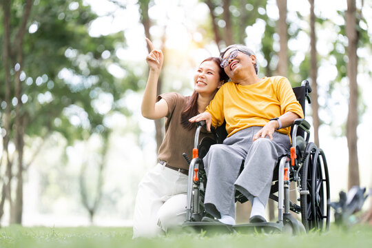 Asian Woman Pointing to the Sky with Her Senior Mother in Wheelchair