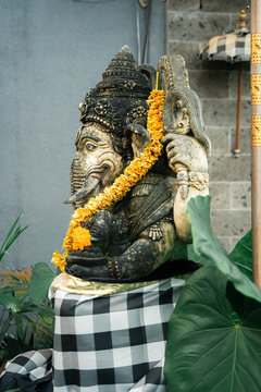 Lord Ganesha sitting in meditating yoga pose at Villa entrance. Decorated for religious festival by orange flowers. Luck and Success's charm. Travel, Culture, Religion concept