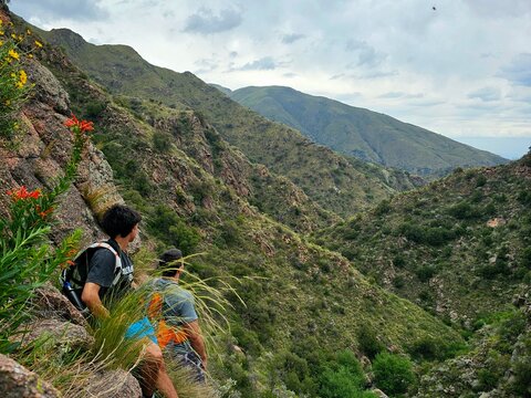 Dos excursionistas contemplando un gran valle verde entre monta&ntilde;as rocosas