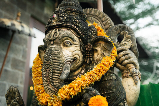 Lord Ganesha sitting in meditating yoga pose at Villa entrance. Decorated for religious festival by orange flowers. Luck and Success's charm. Travel, Culture, Religion concept