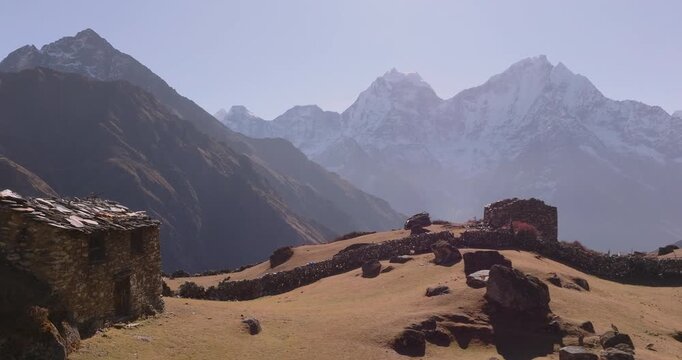 Everest region Nepal, aerial gliding shot of abandoned stone houses and dry alpine meadows in Dole village with mountain valley and distant Khumbu Region, on the way to Everest Base Camp trek.