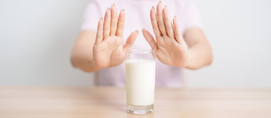 Naklejka premium Lactose intolerance and Milk allergy. woman hand stop and refuse Milk, having abdominal cramps and pain when drink Cow Milk. Symptom stomach ache, Dairy intolerant, Nausea, Bloating, Gas and Diarrhea
