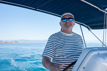 Fototapeta premium Mature man navigating sailboat enjoying summer vacation