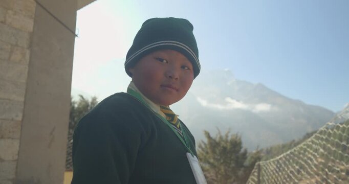 Namche Bazaar Nepal, slow pull out shot of a local Sherpa school boy wearing a green uniform and matching green hat on a bright sunny day in the Everest region.