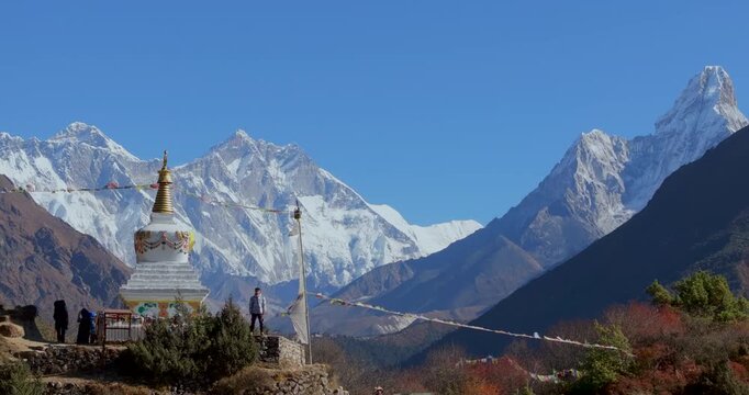 Namche Bazaar, Nepal, push-in shot focusing on a man standing on a stone wall beside a traditional Buddhist stupa with Mount Everest, Lhotse, and Ama Dablam peaks.