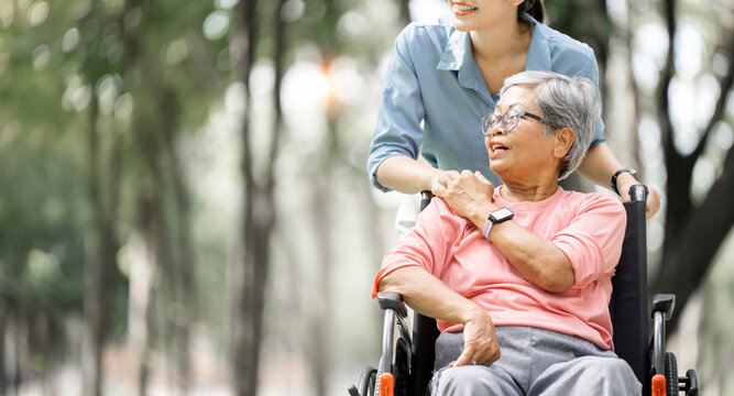 Close-up of Asian Daughter Comforting Senior Mother in Wheelchair at Park