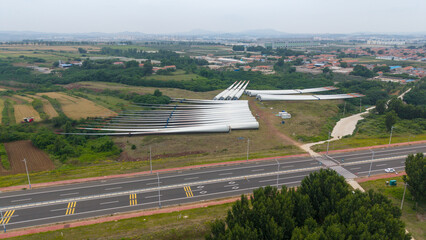 Wind Turbine Blades Stored Near Urban Road and Farmland © Xianshu