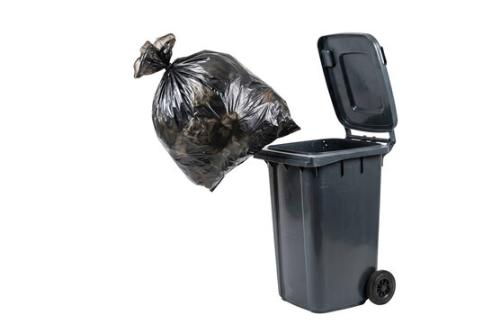 Black garbage bag falling into an open grey wheelie bin