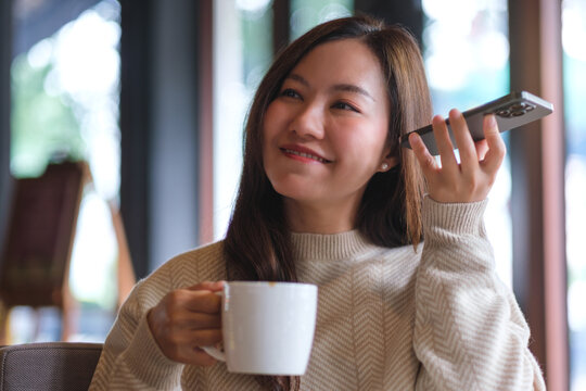 Portrait of a woman listening to a voice message on her phone, conversation on speaker phone in cafe