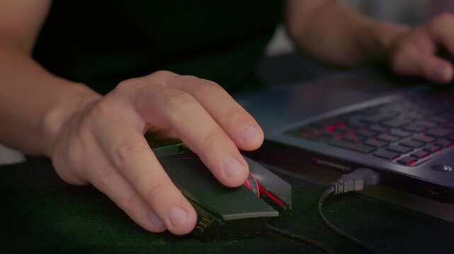 Close-up shot of hands operating a computer mouse while sitting at desk