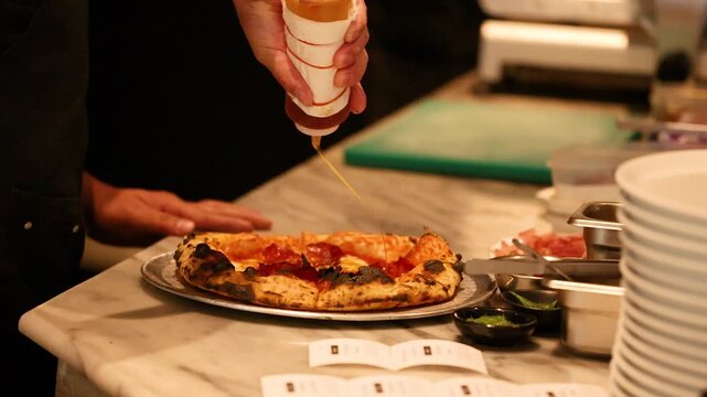 Chef Drizzling Honey Over Fresh Artisan Pepperoni Pizza in Kitchen