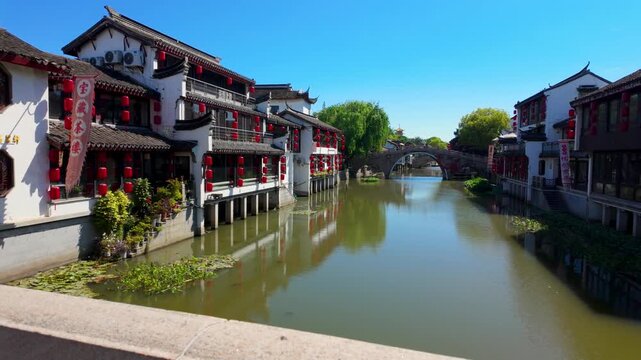 Traditional Chinese canal town with historic buildings and arched stone bridge in sunlight
