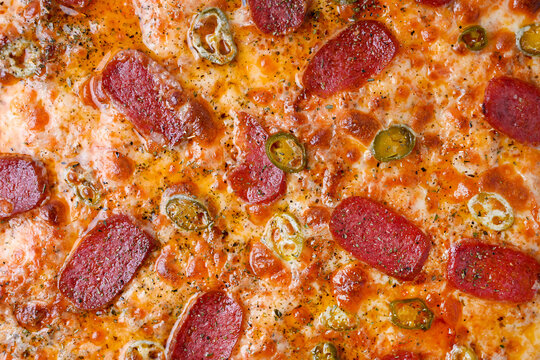 Top-down close-up of pizza texture with sausage and capers, crispy crust, melted cheese, salty capers, spicy sausage slices, Italian pizza detail, food surface pattern, culinary macro shot