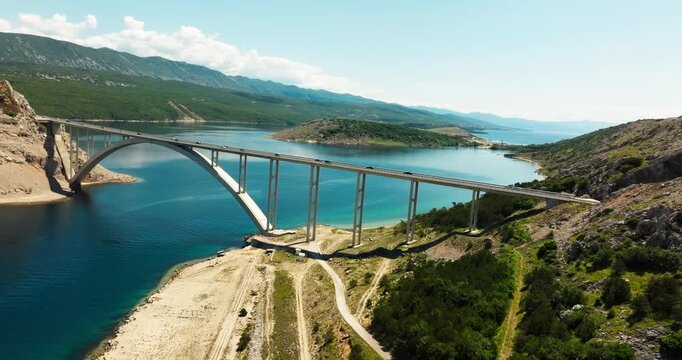Drone view of the iconic Pag Bridge connecting Island to the Croatian mainland. Turquoise Adriatic waters, rocky coastline and modern transport infrastructure on a sunny day.