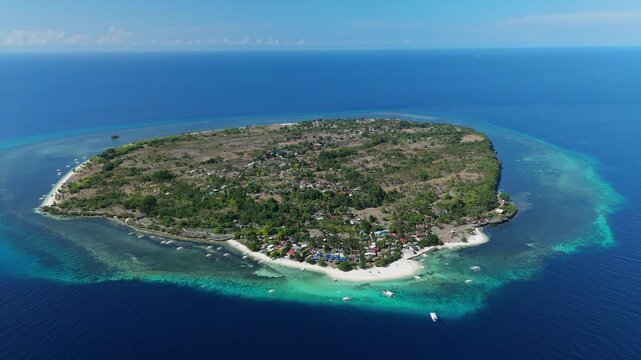 Drone descends toward Pamilacan Island, showing reef, beaches, village, boats, and blue water in Bohol