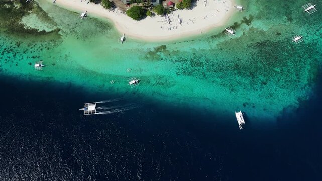 Drone follows and orbits a boat beside Public Pamilacan Beach, showing reef, sand, and blue water in Pamilacan Island, Bohol