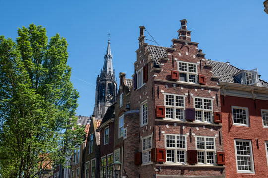 Historic buildings in Delft, Netherlands, Delft City Hall and the Gothic tower of Nieuwe Kerk, blue sky.
