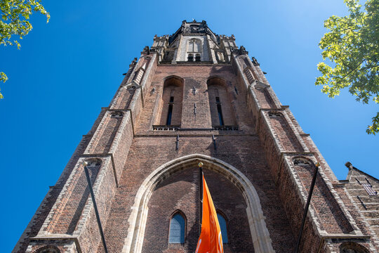 Gothic Brick Tower of Nieuwe Kerk, New Church in Delft Netherlands with orange Flag and clear blue Sky