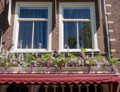 Historic brick townhouses with flowered facade in sunny Delft city centre Netherlands