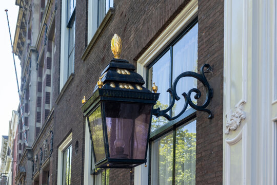 Ornate black and gold wall lantern on brick canal house facade in Delft, Netherlands