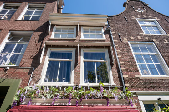 Historic brick townhouses with flowered facade in sunny Delft city centre Netherlands