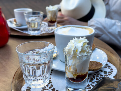 Cappuccino and whipped cream dessert on a sunny outdoor cafe tray in Rotterdam Centrum