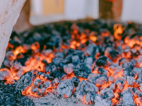 Glowing hot coals and embers inside a traditional clay oven, exhibiting a warm textured surface for artisanal cooking and rustic craft concepts