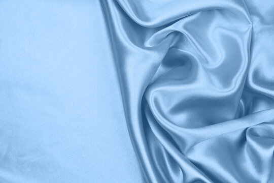 Elegant light blue satin silk fabric texture background with soft folds.