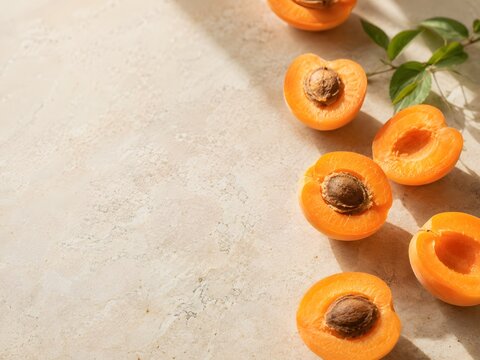 Fresh apricot halves on a neutral stone surface