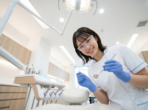 歯科医院で器具を持ち微笑む歯科衛生士の女性