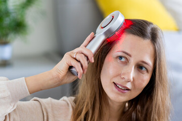 Fototapeta premium Woman using a laser hair comb at home