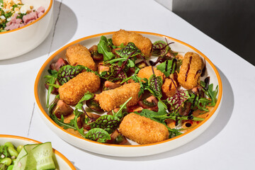 Fototapeta premium Fried cheese salad with tomatoes, arugula and glossy dark glaze in bright summer sunlight for menu