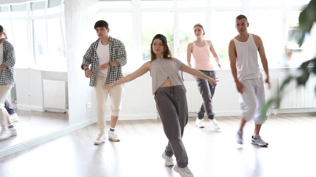 Young man standing performs basic hip hop movements in front of group of students. Developing precise movements, rehearsing arc elements, nae nae moving 