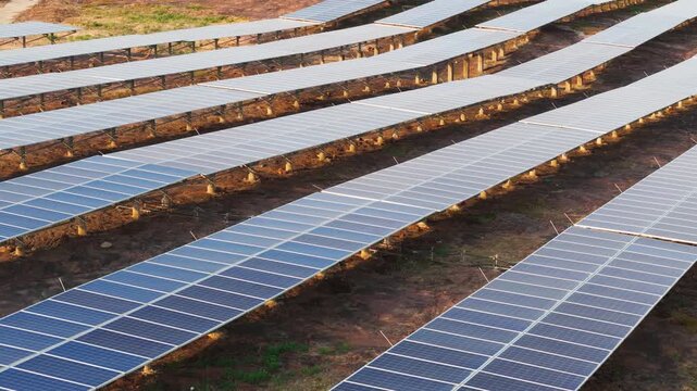 Drone tilt reveal over extensive photovoltaic solar panel arrays at a utility-scale solar farm. Renewable energy infrastructure, clean electricity generation, and sustainable technology.